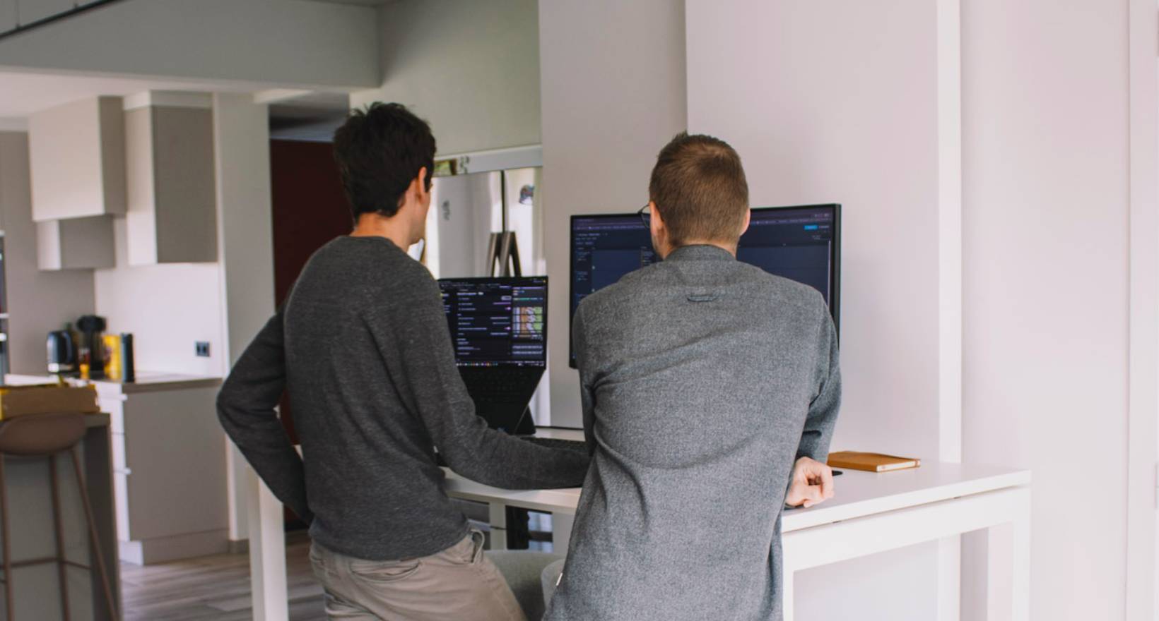 Twee medewerkers van Mad IT poseren voor hun Audi bedrijfswagens voor het hoofdkantoor met Mad IT-logo — softwarebedrijf gespecialiseerd in .NET en Microsoft-technologie met focus op innovatie, teamwork en aangename werksfeer.