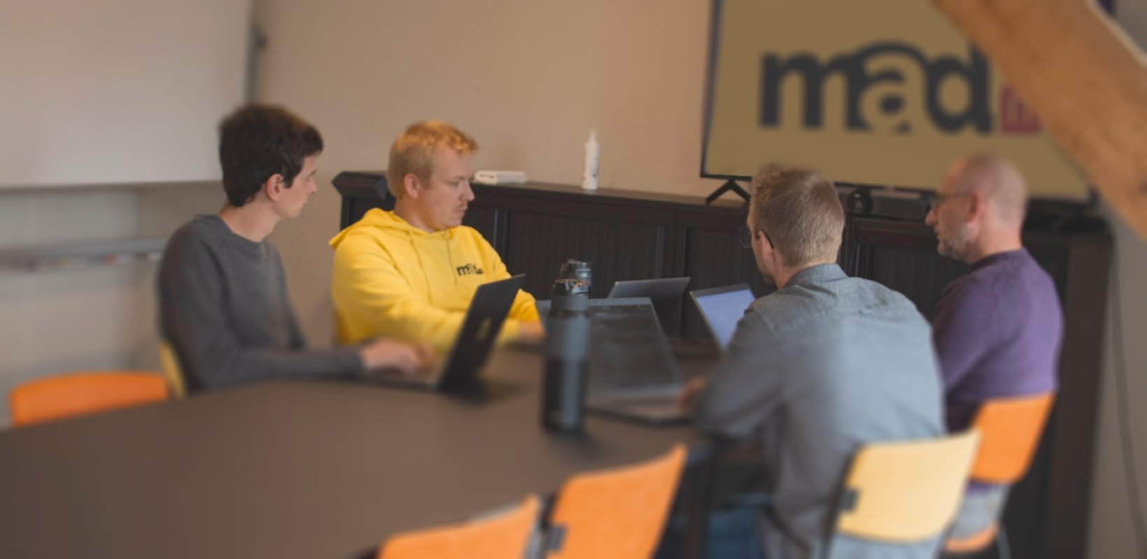 IT-team bespreekt softwaremigratie tijdens hybride vergadering met laptops en videobellen – professionals werken samen aan digitale transformatie.